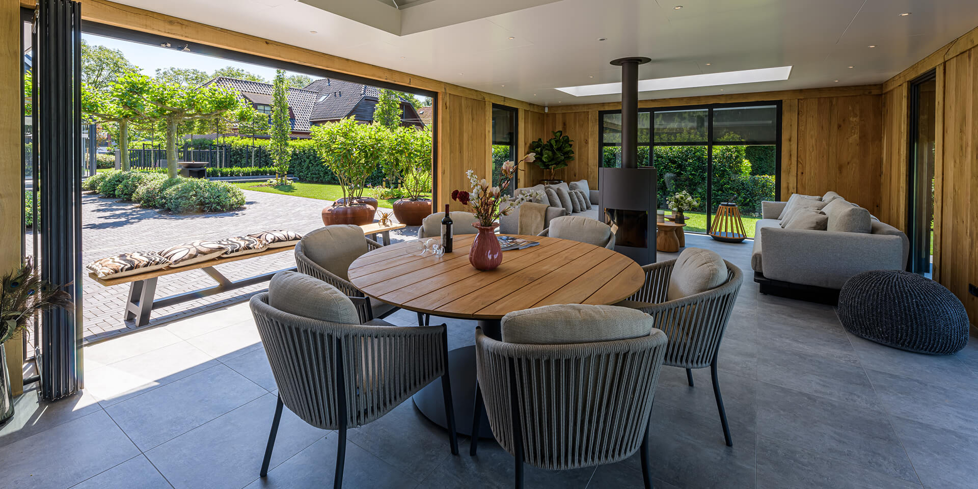 Luxe tuinontwerp met overdekt terras en uitzicht op moderne tuin, ontworpen door tuinarchitect William de Boet.