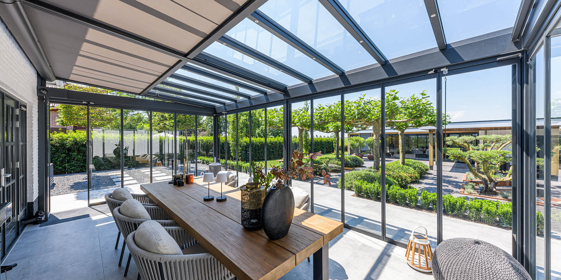 Moderne glazen overkapping met uitzicht op een strakke tuin, ontworpen door tuinarchitect William de Boet.